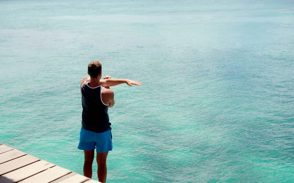 Αθλητής κάνει ασκήσεις στην αποβάθρα του ωκεανού — Φωτογραφία Αρχείου