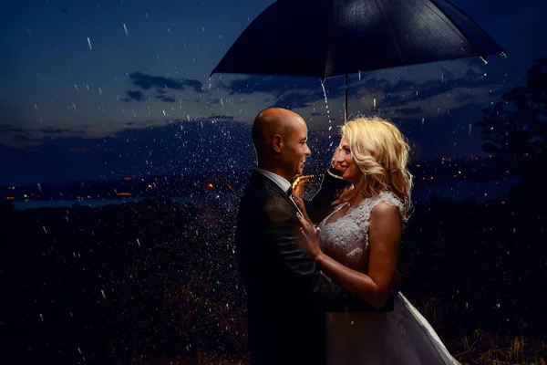 Casal recém-casado de pé sob guarda-chuva — Fotografia de Stock