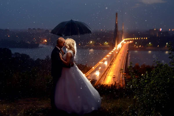 Newlywed couple kissing under umbrella — Stock Photo, Image