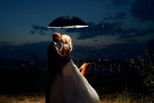 Brautpaar küsst sich unter Regenschirm — Stockfoto