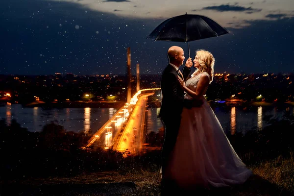 Casal recém-casado de pé sob guarda-chuva — Fotografia de Stock