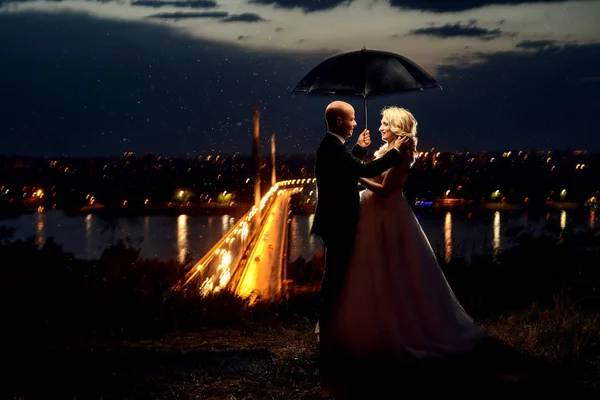 Newlywed couple standing under umbrella — Stock Photo, Image