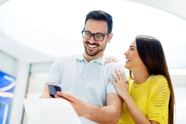 Pareja en la tienda electrónica celebración de teléfonos inteligentes — Foto de Stock