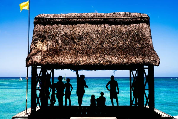 Silhouetten von Menschen, die sich am Meer entspannen — Stockfoto