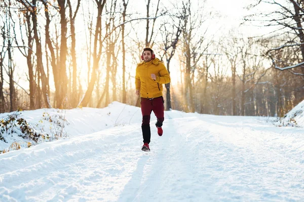 Hombre en ropa deportiva corriendo en el parque nevado — Foto de Stock