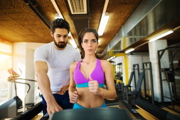 Mulher correndo em esteira e personal trainer — Fotografia de Stock