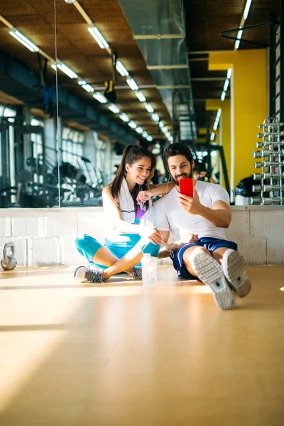 Sorrindo casal com telefone celular no ginásio — Fotografia de Stock