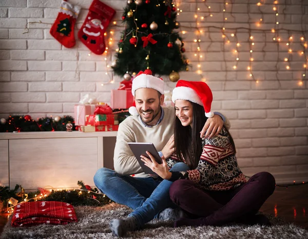 Улыбающаяся пара с планшетным ПК на Рождество — стоковое фото