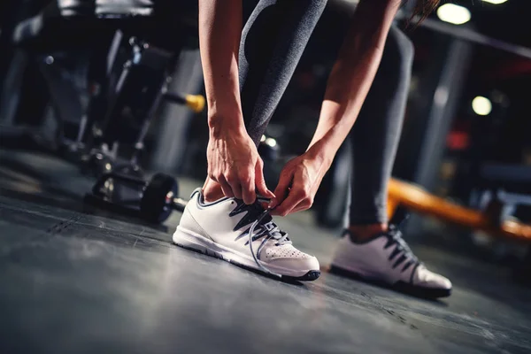 Женщина завязывает шнурки в спортзале — стоковое фото