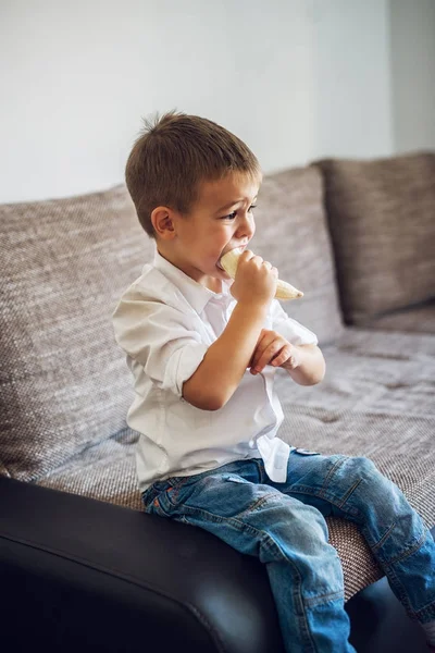 Anak Kecil Lapar Makan Pisang Duduk Sofa Rumah — Stok Foto