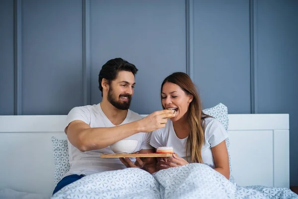 Attraktiver Junger Glücklicher Mann Füttert Freundin Hause Bett — Stockfoto