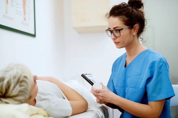 Aantrekkelijke Verpleegkundige Met Bril Zit Van Vrouwelijke Patiënt Met Medicijnen — Stockfoto