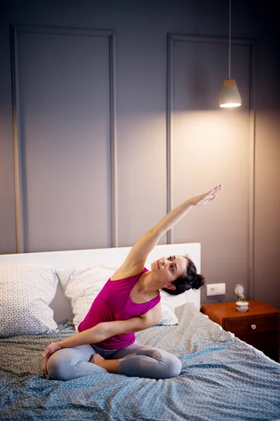 attractive sporty woman doing seated yoga pose in bed