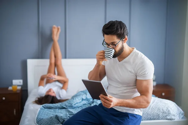 Strong Muscular Man Drinking Coffee Using Tablet Sitting Bed His — Stock Photo, Image