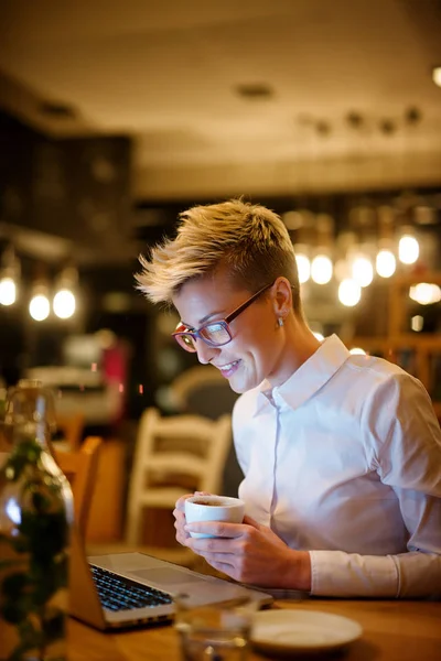 年轻漂亮的女商人在咖啡馆里使用笔记本电脑 时尚女性戴眼镜 通过耳机听音乐 — 图库照片
