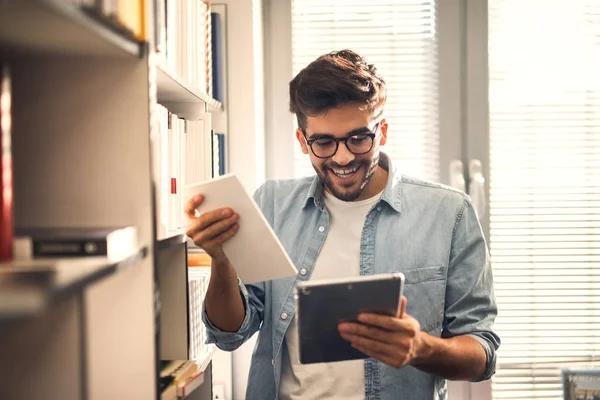 Tablet Kullanarak Kütüphane Içinde Bookshelf Kitap Seçimi Genç Neşeli Yakışıklı — Stok fotoğraf