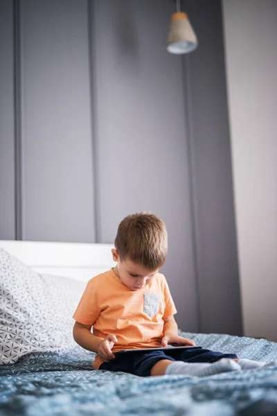 Söt Nyfikna Småbarn Pojke Sitter Sängen Med Tabletpc Och Spelar — Stockfoto