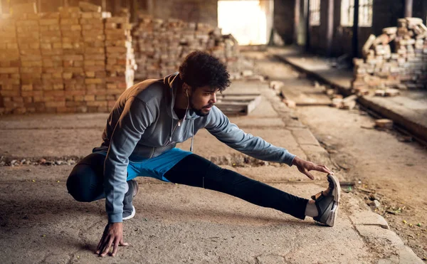 Retrato Hombre Afro Americano Motivado Estirándose Hangar Abandonado Con Auriculares — Foto de Stock