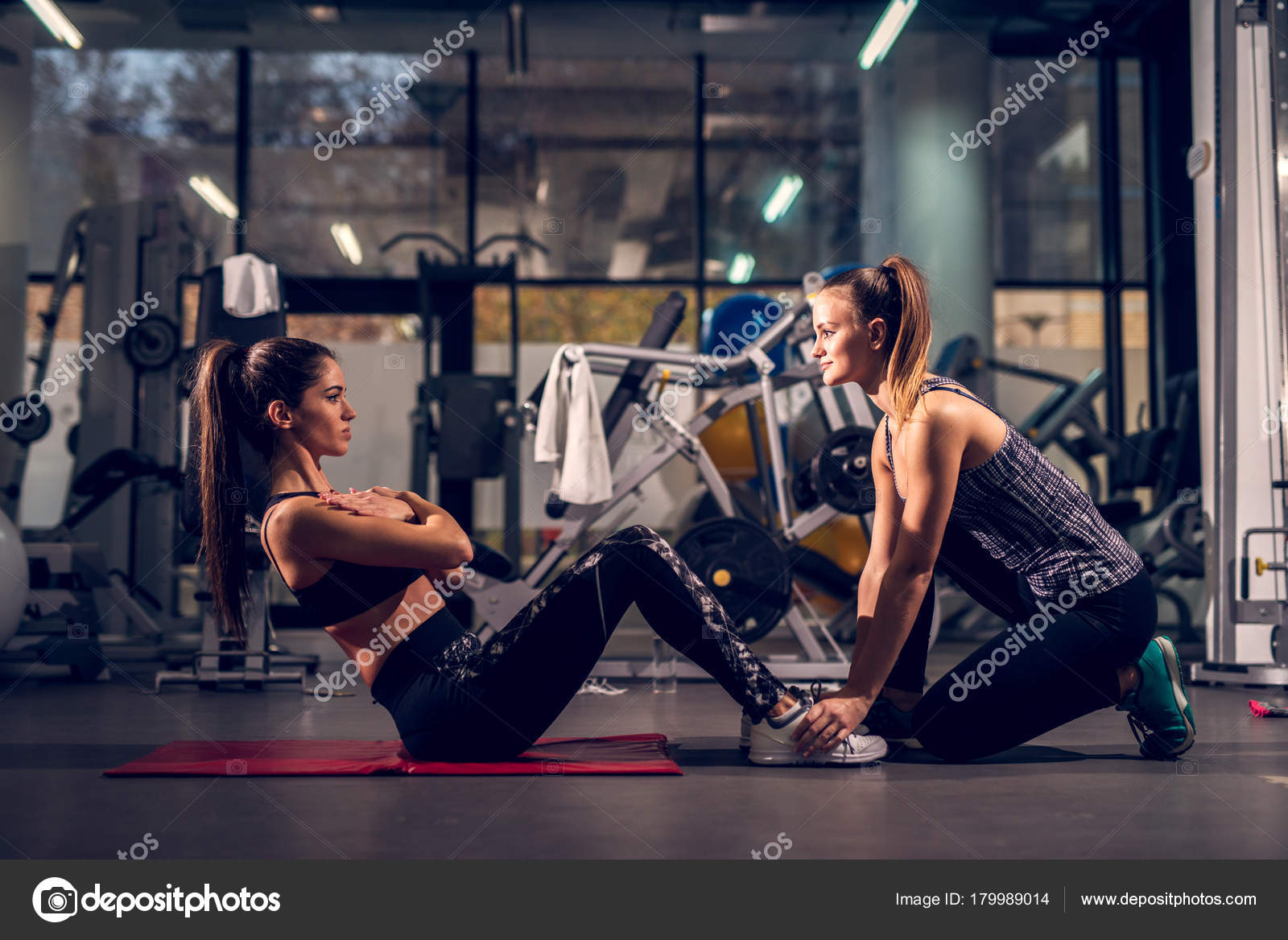 Young Woman Exercising While Her Female Personal Trainer Assisting