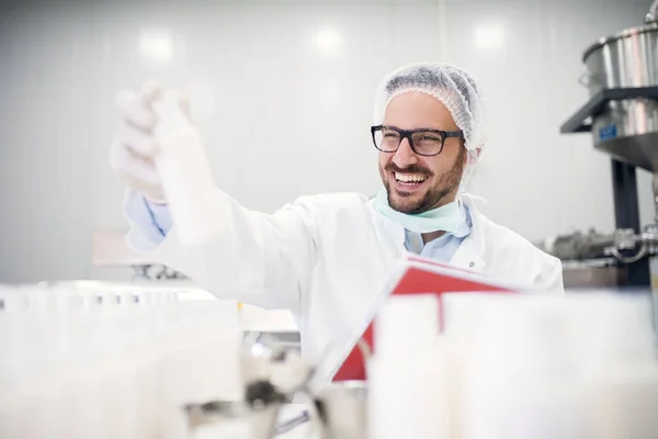 professional happy scientist holding clipboard and white bottle in laboratory