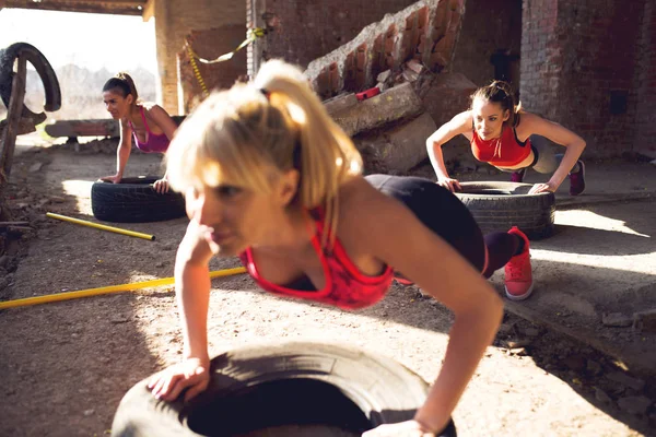 Three Fit Sporty Young Women Doing Push Ups Tires Hangar — Stock Photo, Image