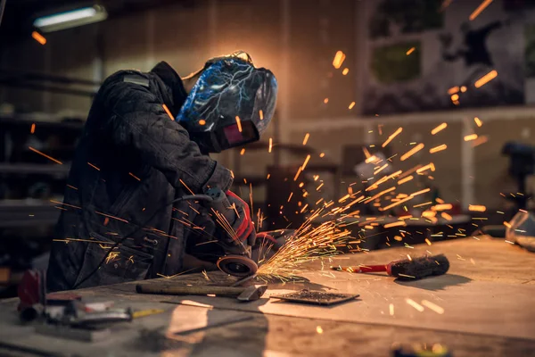 professional welder with protection mask working in workshop, bright sparks