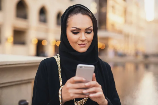 美丽的穆斯林年轻女子在黑色头巾使用智能手机在城市 — 图库照片