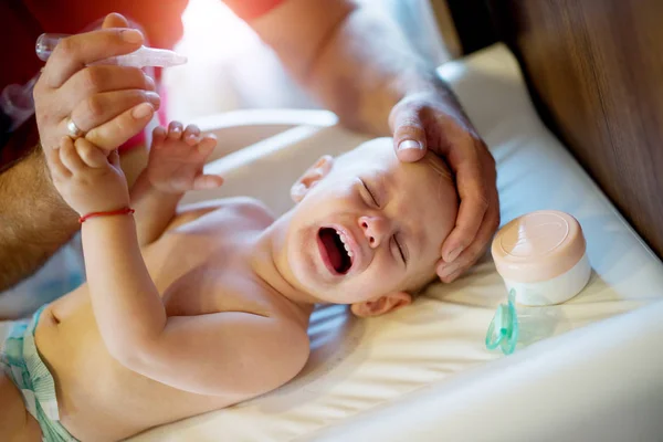 かわいい赤ちゃんがおしゃぶりをベッドに横になっている泣いて 鼻は彼を与えるしようとすると 父が値下がりしました — ストック写真