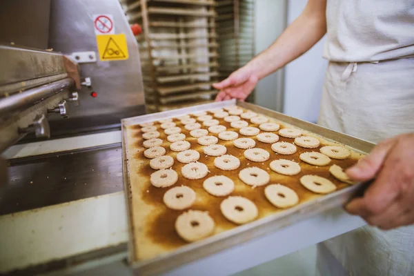 クッキー工場 食品業界での製造工程 トレイから焼きたてのクッキーを取って手袋の女 — ストック写真