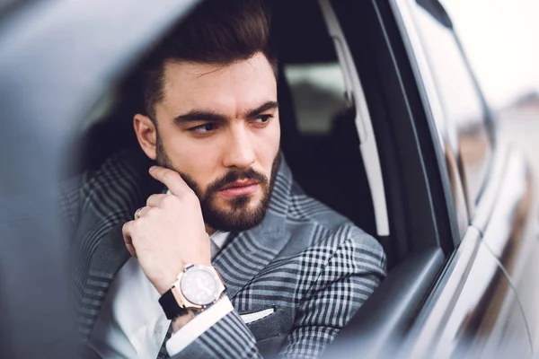 高価な車の窓の外を見てのスーツでハンサムなひげを生やした実業家 — ストック写真