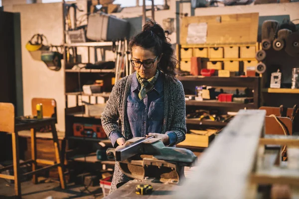 happy professional female carpenter with steel vise in workshop