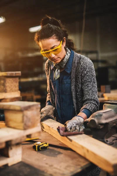 hardworking female carpenter working with wood in workshop