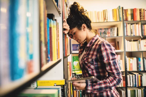図書館の本棚から本を選択する若い女性学生 — ストック写真