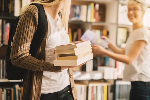 図書館で本の山を持って魅力的な女子学生の肖像画 — ストック写真