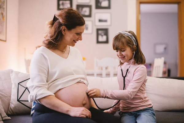 Toddler Ładna Dziewczyna Słuchania Brzuch Matki Ciąży Przez Stetoskop — Zdjęcie stockowe