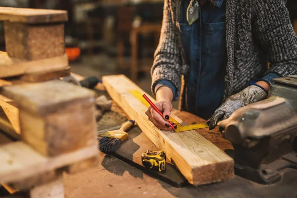辛勤工作的女木匠在车间里用尺子和木头做记号 — 图库照片