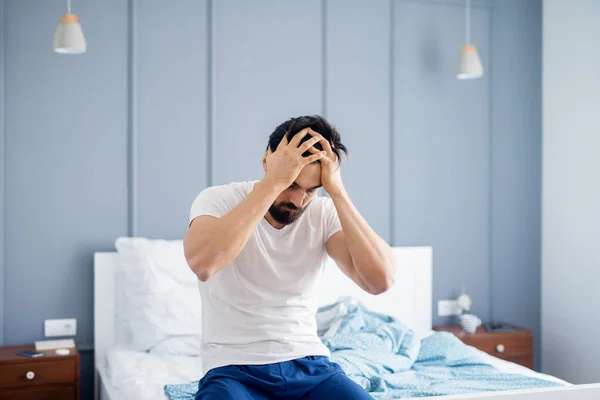 Attraktiver Mann Sitzt Auf Dem Bett Und Hält Schmerzhaften Kopf — Stockfoto