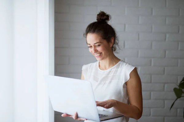 smiling businesswoman using laptop near window at home
