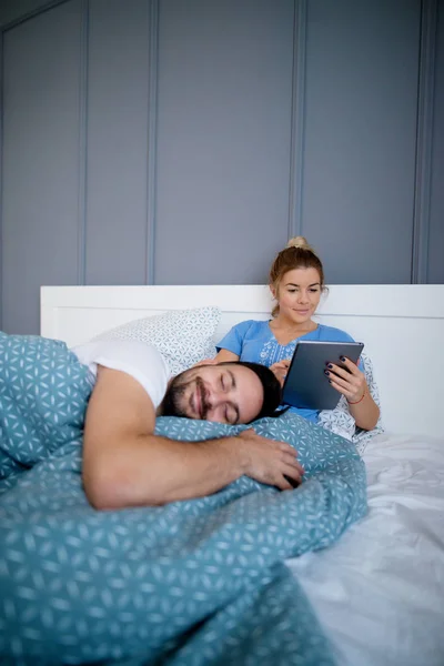 Mujer usando tableta y novio durmiendo — Foto de Stock