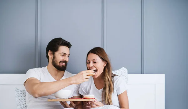 Atractivo Joven Feliz Hombre Alimentación Novia Cama Casa — Foto de Stock