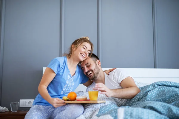 careful romantic young woman bringing breakfast in bed to boyfriend at home