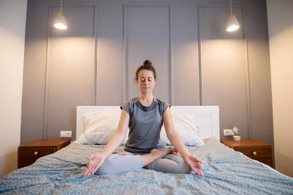 beautiful healthy woman doing yoga meditation in bed at home