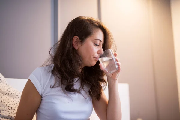 Nemocná Žena Sedí Posteli Doma Trpí Bolestí Hlavy Pitné Vody — Stock fotografie