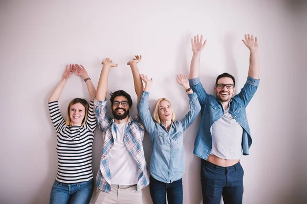 Gruppo Giovani Sorridenti Appoggiati Muro Con Braccia Alzate — Foto Stock