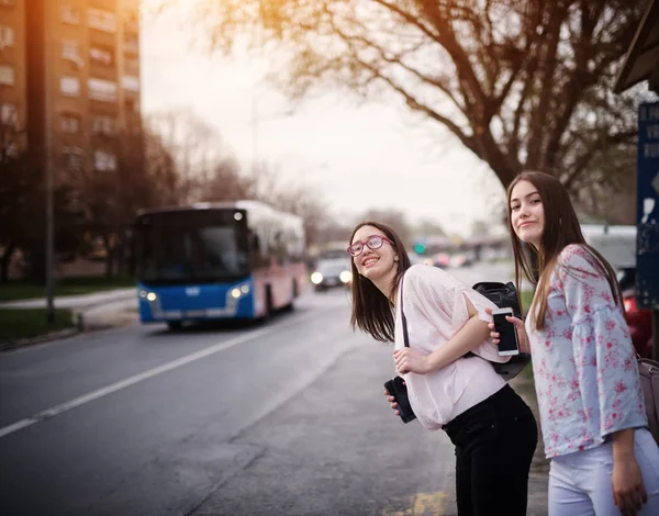 Две Очаровательные Милые Школьницы Ждут Автобус Рюкзаками Автобусной Станции — стоковое фото