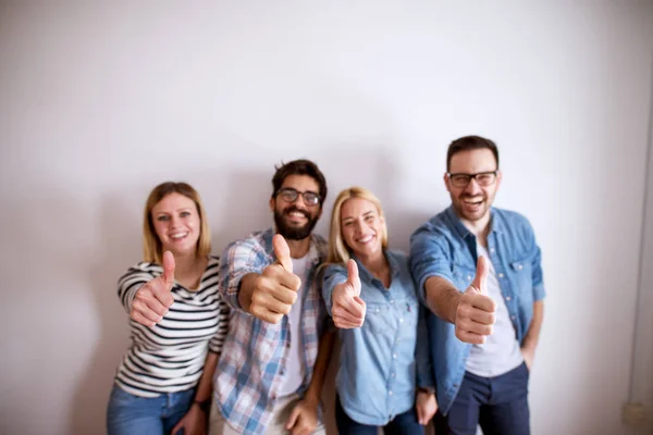 group of joyful excited young people holding thumbs up, happy team and coworkers concept