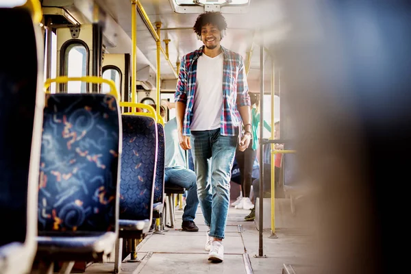 young cheerful man walking in bus