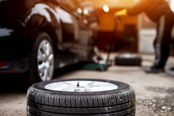 Neuer Reifen Auf Gehweg Neben Auto Garage Mechaniker Wechselt Reifen — Stockfoto
