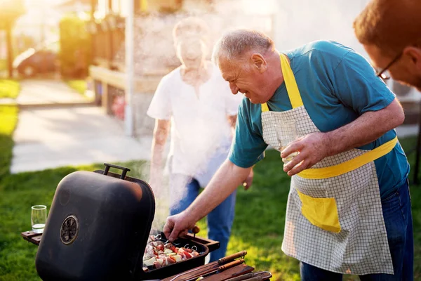Älterer Glücklicher Mann Kocht Fleisch Grill — Stockfoto