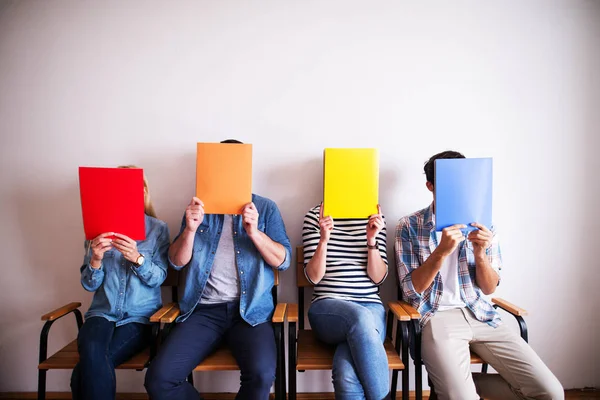 Grupo Jovens Cobrindo Rostos Com Pastas Coloridas — Fotografia de Stock